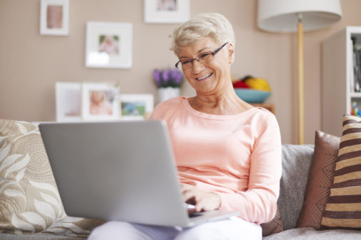 Senior woman relaxing with laptop on sofa